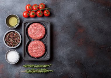 Plastik tepsi ile baharat ve otlar ile ev yapımı çiğ kıyma sığır eti hamburger. Üstten görünüm ve metin için yer.
