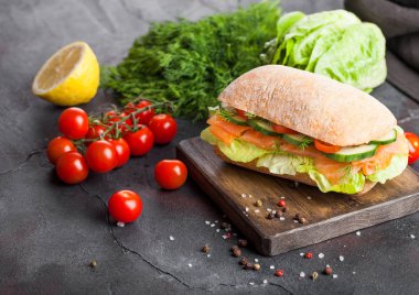 Marul ve salatalığın üzerinde taş zemin üzerine vintage Doğrama tahtası ile taze sağlıklı somon sandviç. Kahvaltı snack. Taze domates, dereotu ve limon.