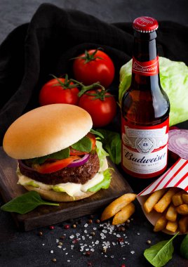 Londra, İngiltere - 05 Ekim 2018: Şişe, Budweiser özgün bira taze sığır eti hamburger ve patates kızartması ile tabloda koyu arka plan üzerinde sebzeli.