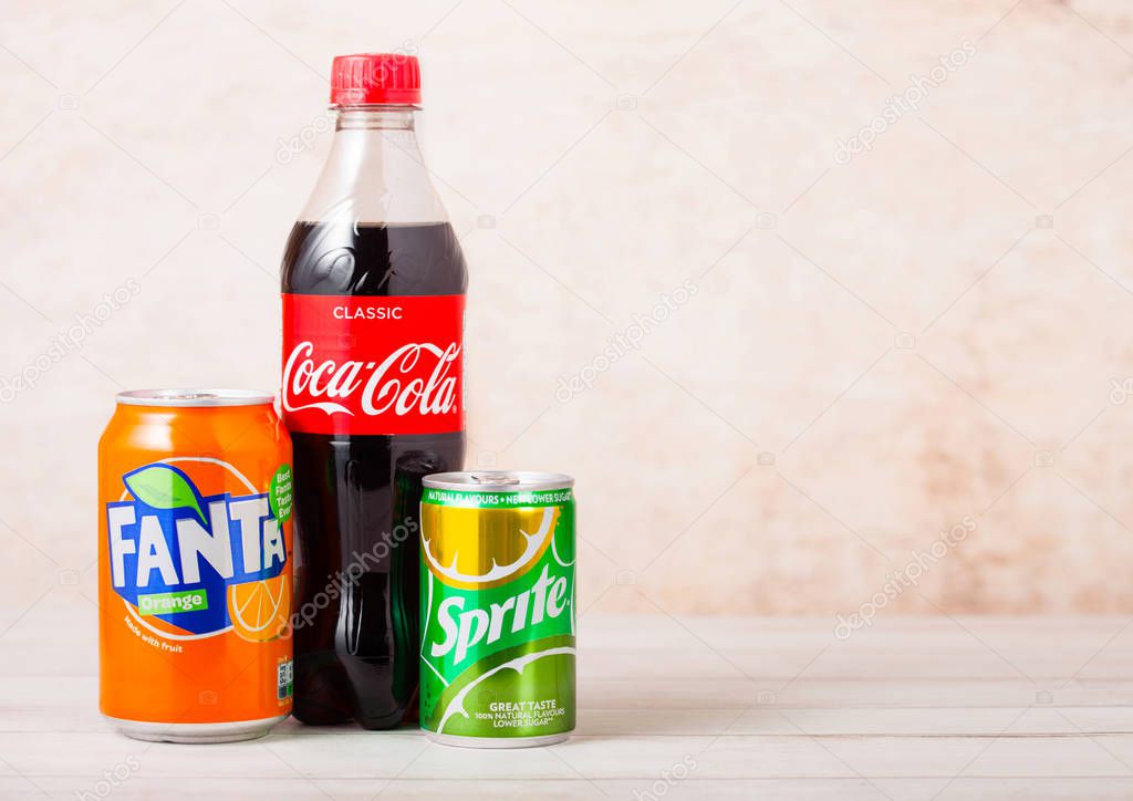 LONDON, UK - AUGUST 03, 2018: Plastic bottle and aluminium cans of Coca Cola and Fanta and Sprite soft drink on wood. Most popular drinks in the world.