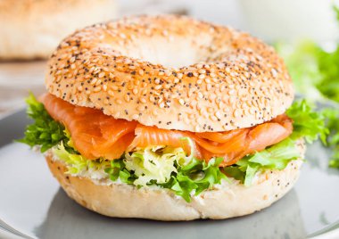Taze sağlıklı simit sandviç somon, ricotta ve marul ışık mutfak masa arka planda gri plaka. Sağlıklı bir diyet yemek.