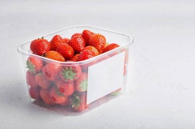 Plastik tepsi konteyner taş mutfak masa arka plan üzerinde taze organik sağlıklı çilek.