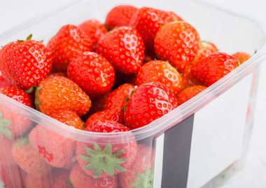 Plastik tepsi konteyner taş mutfak masa arka plan üzerinde taze organik sağlıklı çilek.