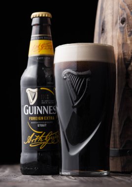 LONDON, UK - 27 Nisan 2018: eski ahşap fıçının yanında şişe ve orijinal Guinness fıçısı. Guinness birası 1759 'dan beri Dublin, İrlanda' da üretiliyor..