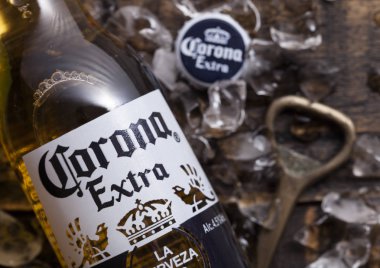 Londra, İngiltere - 27 Nisan 2018: Cam şişe, Corona ilave bira şişe açacağı ve buz küpleri ile ahşap arka plan üzerinde. Corona, Grupo Modelo tarafından üretilen.