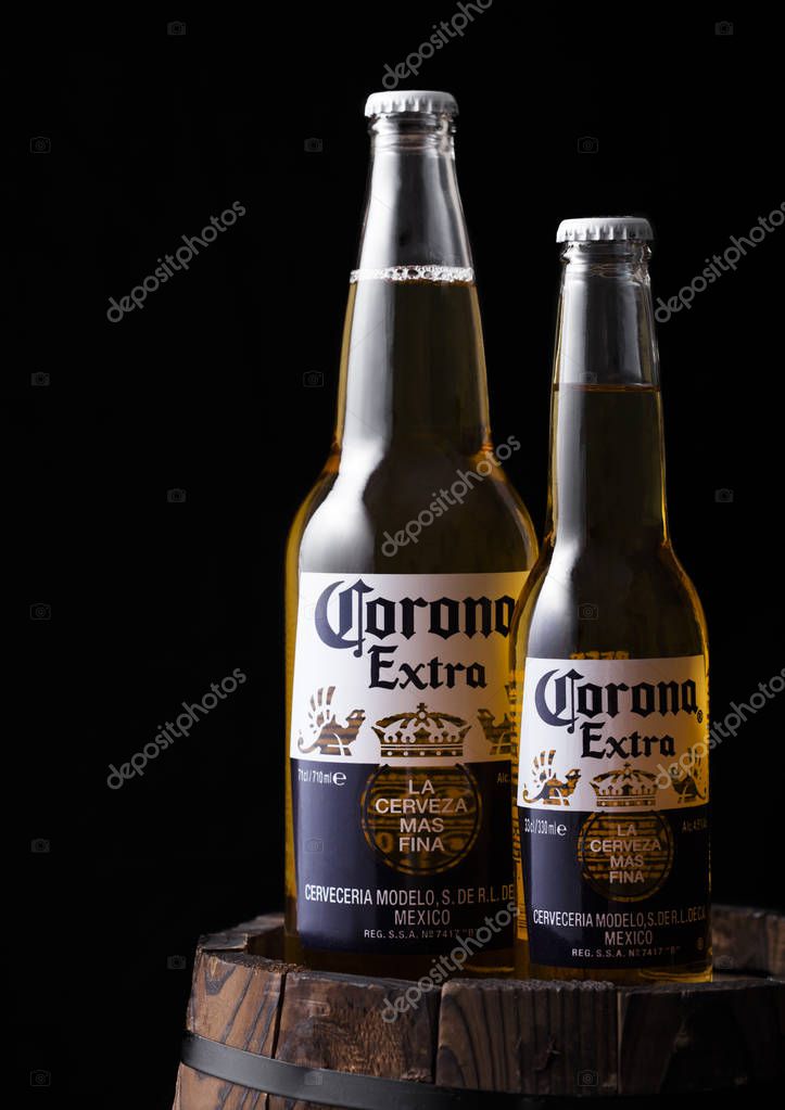 LONDON, UK - APRIL 27, 2018: Bottles of Corona Extra Beer on old wooden barrel on black background. Corona, produced by Grupo Modelo.