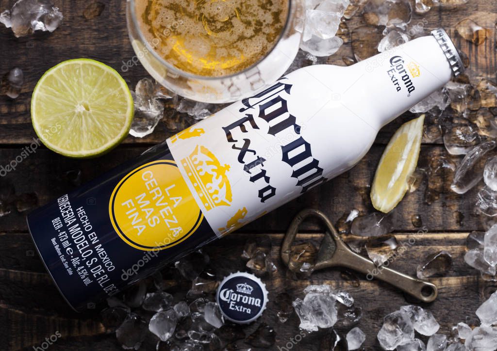 LONDON, UK - APRIL 27, 2018: Steel Bottle of Corona Extra Beer on wooden background with bottle opener and ice cubes. Corona, produced by Grupo Modelo.