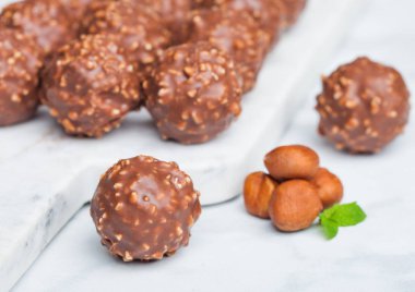 Fındık parçaları ve mermer zemin üzerine nane yaprağı ile lüks çikolata şekerleme.