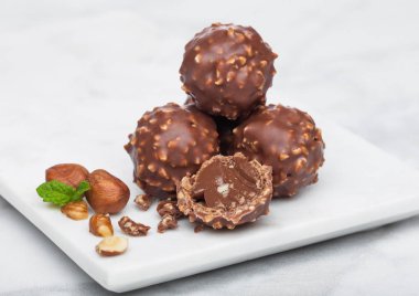 Fındık parçaları ve mermer zemin üzerine nane yaprağı ile lüks çikolata şekerleme.