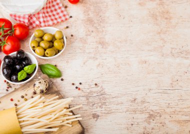 Bıldırcın yumurtalı, domates soslu ve ahşap kaplamalı ev yapımı makarna. Klasik İtalyan köy yemekleri işte. Sarımsak, şampiyon, siyah ve yeşil zeytin, yağ ve spatula.