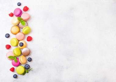 Tatlı pasta macaron veya ahududu ve taş mutfak arka plan üzerinde yaban mersini ile acıbadem kurabiyesi. Üstten görünüm. 