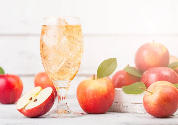 Glass of homemade organic apple cider with fresh apples in box on wooden background, Glass with ice cubes