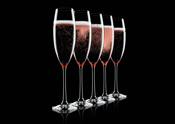 Rose pink champagne glasses with bubbles on black background with reflection