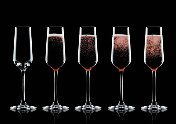 Rose pink champagne glasses with bubbles on black background with reflection