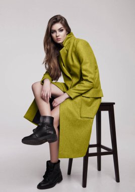 Güzel genç kız üzerinde uzun gri ceket gri arka plan üzerinde