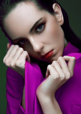 Yeşil arka plan üzerinde menekşe mor uzun ceket giyen ıslak saçlı manken. Moda portre.