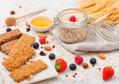 Organik tahıl granola bar tatlım kaşık ve mermer masa artalanını yulaf ve keten havluda kavanoz ile mermer gemide çilek ile.