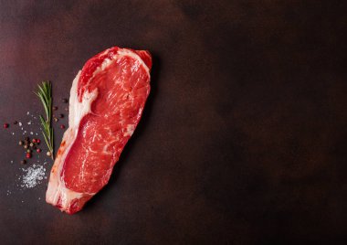 Ham sığır bonfile paslı arka plan üzerinde. Tuz ve biber ile taze biberiye.