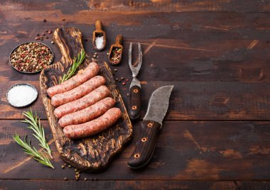 Ham sığır eti ve domuz sosis vintage bıçak ve çatal ahşap arka plan üzerinde eski kesme tahtası üzerinde. Tuz ve karabiber biberiye ile.