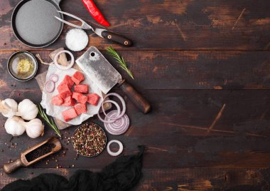 Ham yalın güveç dana domuz biftek vintage et balta ve çatal ile ahşap arka plan üzerine doğranmış. Tuz ve karabiber taze biberiye, kırmızı soğan ve sarımsak ile.