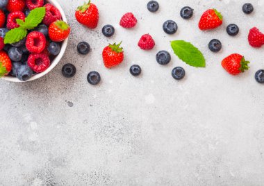 Mutfak Masa arka plan üzerinde beyaz seramik kase taze ham organik çilek. Metin için yer. Çilek, ahududu, yaban mersini ve nane yaprağı