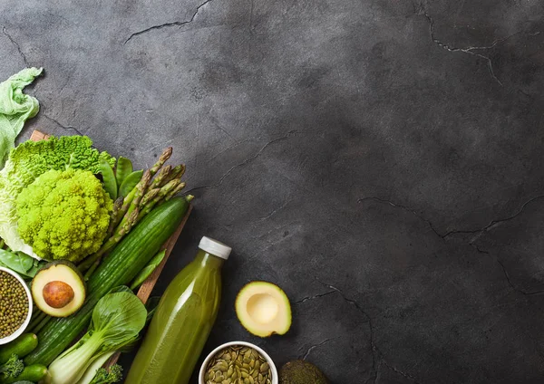 Çeşitli yeşil koyu arka plan üzerinde ham organik sebze tonda. Avokado, karnabahar ve salatalık kesilmiş fasulye ve güler yüzlü şişe ile.