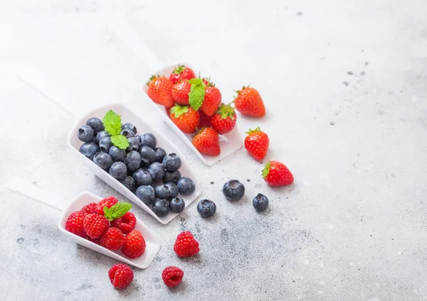 Beyaz kaşık kaşık mutfak masasının üzerinde taze ham organik çilek. Metin için yer. Üstten görünüm. Çilek, ahududu, yaban mersini ve nane yaprağı