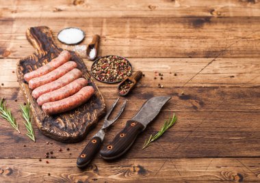 Ham sığır eti ve domuz sosis vintage bıçak ve çatal ahşap arka plan üzerinde eski kesme tahtası üzerinde. Tuz ve karabiber biberiye ile.