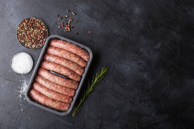 Tuz ve biber siyah arka plan üzerine ile plastik tepsi ham sığır eti ve domuz sosis.