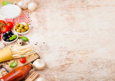 Bıldırcın yumurtalı, domates soslu ve ahşap kaplamalı ev yapımı makarna. Klasik İtalyan köy yemekleri işte. Sarımsak, şampiyon, siyah ve yeşil zeytin, yağ ve spatula.