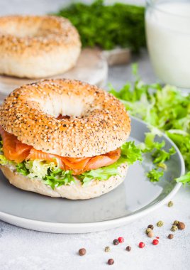 Taze sağlıklı simit sandviç somon, ricotta ve marul ışık mutfak masa arka planda gri plaka. Sağlıklı bir diyet yemek.