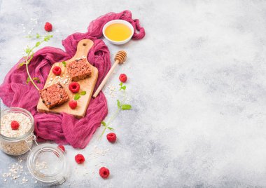 Organik tahıl meyve çilek tatlım kaşık ve yulaf mor kumaş üzerine kavanoz ile vintage gemide granola bar. Çilek, ahududu ve nane yaprağı ve kase bal ile yaban mersini. Üstten görünüm