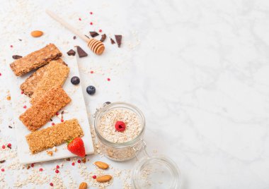 Çilek tatlım kaşık ve yulaf mermer masa arka plan üzerinde kavanoz ile mermer Yönetim Kurulu ile organik tahıl granola bar. Metin için yer. Üstten görünüm. Çilek, ahududu ve badem fındık ile yaban mersini.