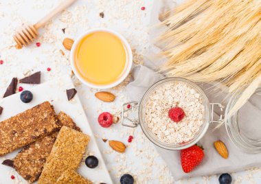 Organik tahıl granola bar tatlım kaşık ve mermer masa artalanını yulaf ve keten havluda kavanoz ile mermer gemide çilek ile.