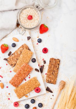 Organik tahıl granola bar tatlım kaşık ve mermer masa artalanını yulaf ve keten havluda kavanoz ile mermer gemide çilek ile.