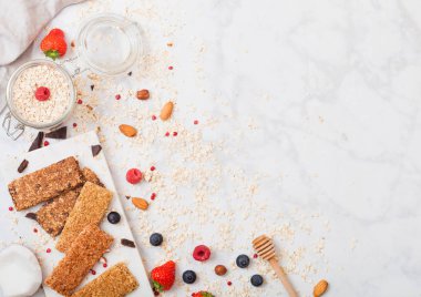 Organik tahıl granola bar tatlım kaşık ve yulaf ve keten havlu mermer zemin üzerine kavanoz ile mermer gemide çilek ile.