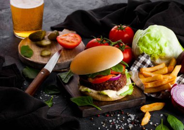 Taze et burger sosu ve sebze ve bardak bira zanaat bira patates cipsi kişiler üzerine taş mutfak arka plan ile.