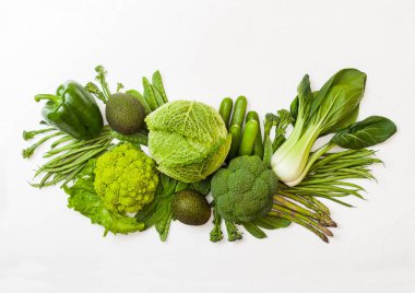Çeşitli yeşil beyaz arka plan üzerinde ham organik sebze tonda. Avokado, lahana, brokoli, karnabahar ve salatalık ile kesilmiş ve gevşek mung fasulye, pak choi, biber ve marul