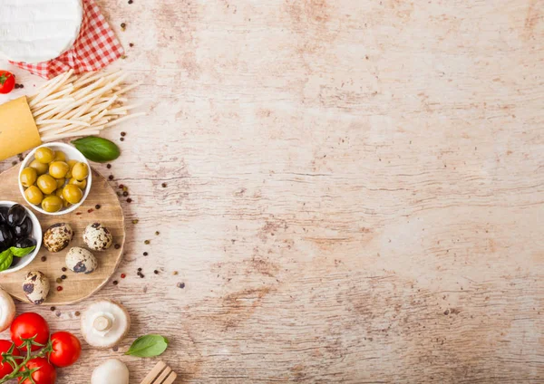 Homemade spaghetti pasta with quail eggs with bottle of tomato sauce and cheese on wood background. Classic italian village food. Garlic, champignons, black and green olives, oil and spatula