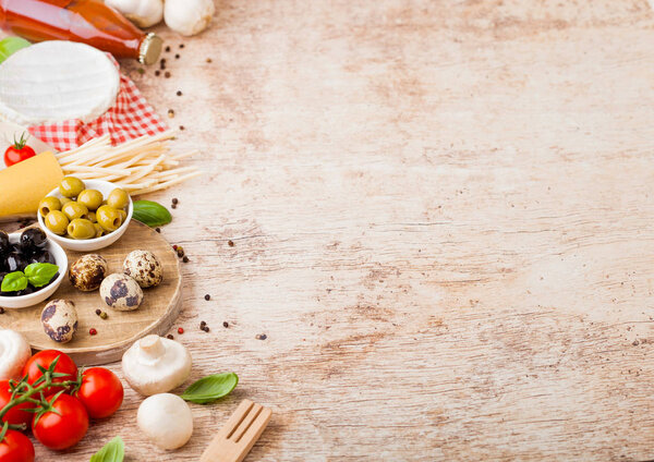 Homemade spaghetti pasta with quail eggs with bottle of tomato sauce and cheese on wood background. Classic italian village food. Garlic, champignons, black and green olives, oil and spatula