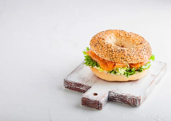 新鲜健康的百吉饼三明治与三文鱼 里科塔和生菜在石头厨房桌子背景的老式切菜板 — 图库照片