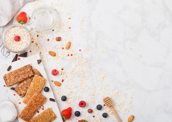 Organik tahıl granola bar tatlım kaşık ve yulaf ve keten havlu mermer zemin üzerine kavanoz ile mermer gemide çilek ile.