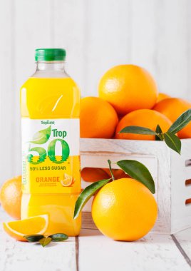 Londra, İngiltere - 15 Ocak 2019: Plastik şişe taze Tropicana tropikal turuncu suyu Beyaz ahşap kutusunda taze çiğ portakal ile.