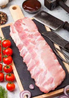 Yönetim Kurulu ve vintage et çatal ve bıçak ışık taş arka plan üzerinde doğrama üzerinde taze çiğ Domuz kaburga. Taze domates ve kırmızı soğan sarımsak, tuz ve biber ile.