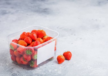 Plastik tepsi konteyner taş mutfak masa arka plan üzerinde taze organik sağlıklı çilek.
