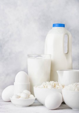 Beyaz arka planda taze süt ürünleri. Bir kavanoz süt, bir kase ekşi krema, süzme peynir, un ve mozzarella. Yumurta ve peynir..