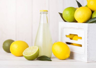 Organik taze limon ve limon suyu çiğ limon ve limes Beyaz ahşap kutusunda ile cam şişe