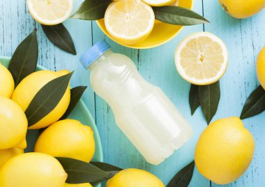Organik taze limon suyu mavi ahşap zemin üzerine çiğ limon ile plastik şişe. Üstten Görünüm