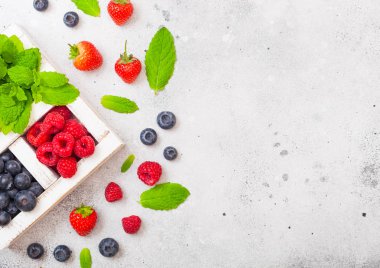 Mutfak Masa arka plan üzerinde beyaz wintage ahşap kutusunda taze ham organik çilek. Metin için yer. Çilek, ahududu, yaban mersini ve nane yaprağı