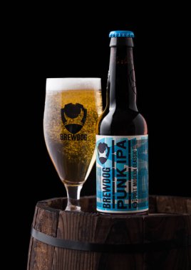 Londra, İngiltere - 06 Şubat 2019: Şişe ve bardak siyah arka plan üzerine eski ahşap varil üzerinde Brewdog bira dan Punk IPA bira.